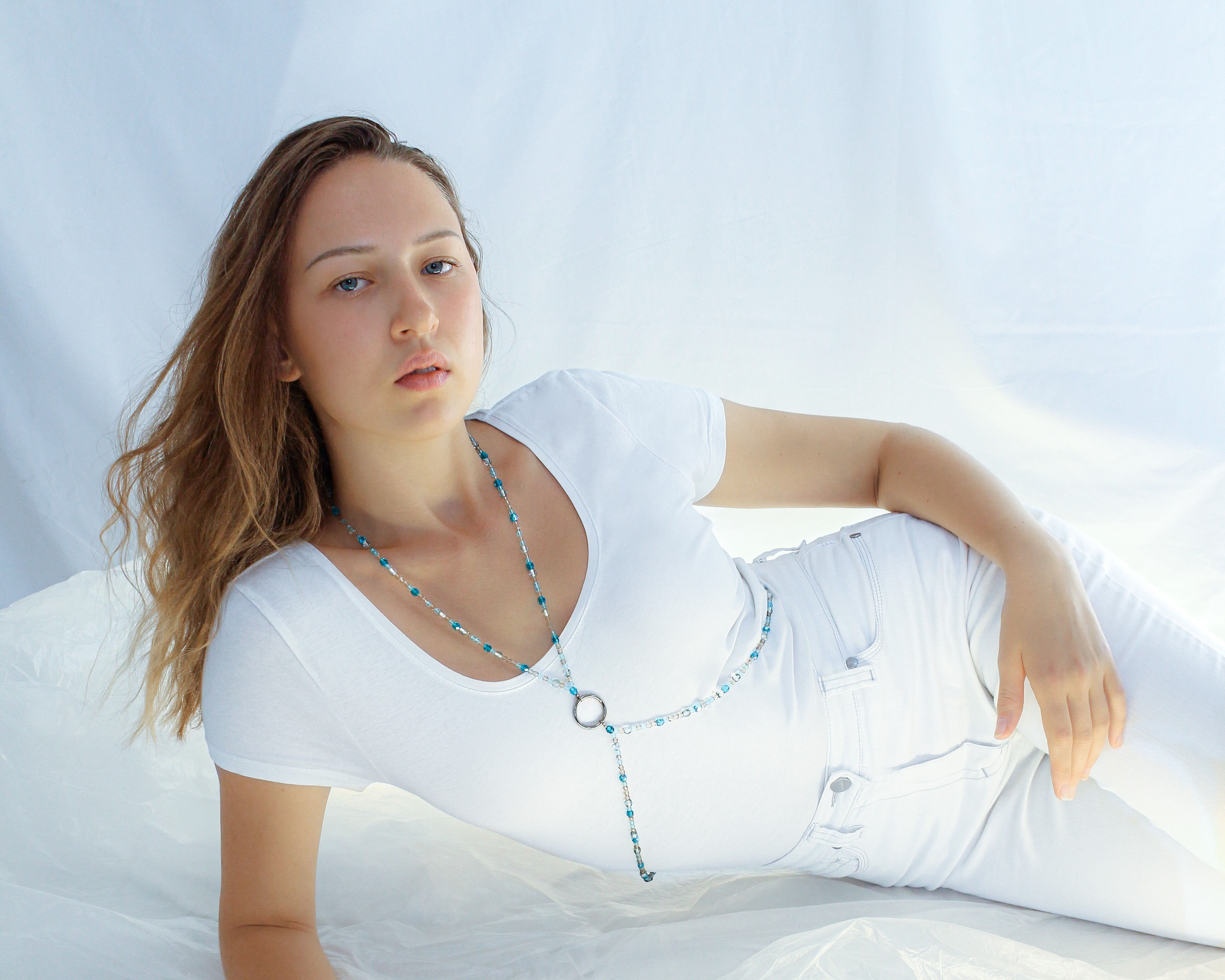 Azure Collection Photo of female model Luisa Hill  wearing SOIRA jewlry. Models are dressed in white in front of white background. SOIRA body chain