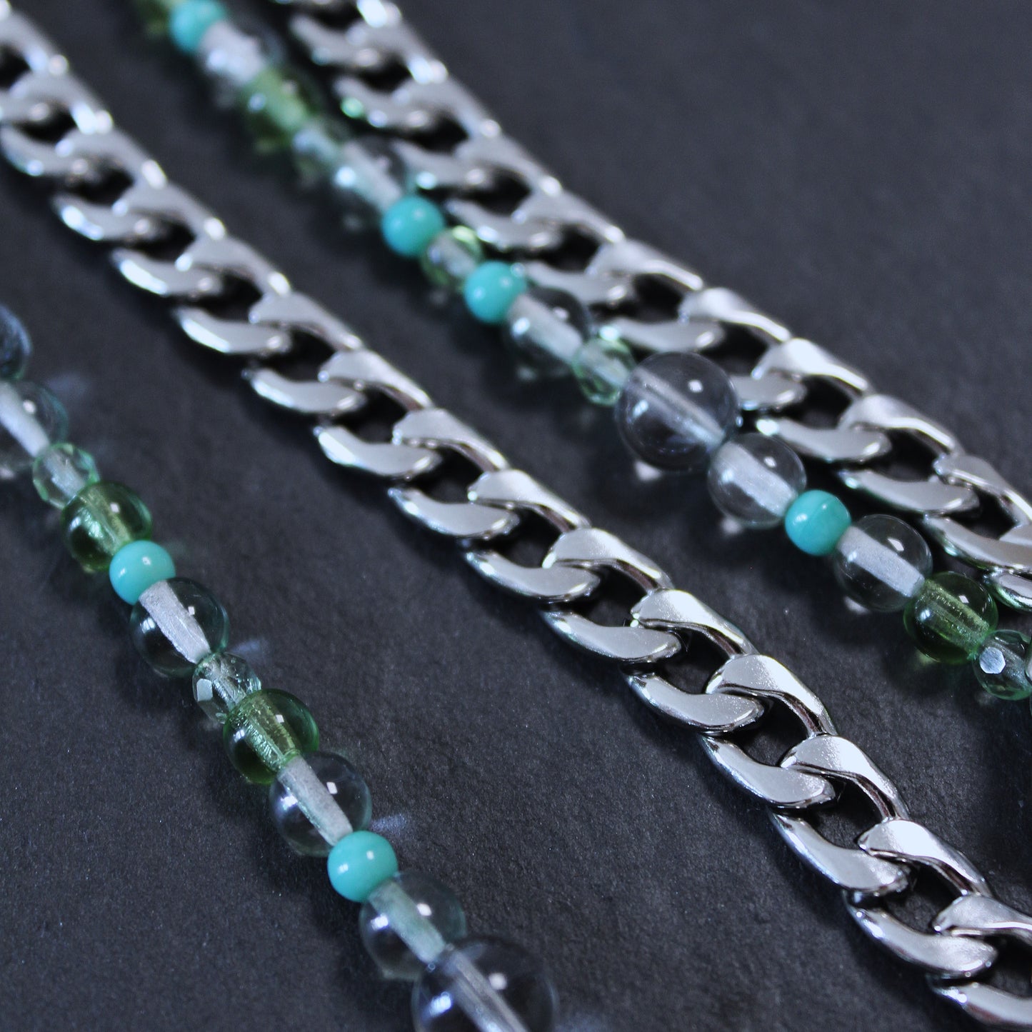 Detail Foto von einem SOIRA Produkt auf dunklem Hintergrund. Produktfoto Zoom. Edelstahlkette und Glasperlen